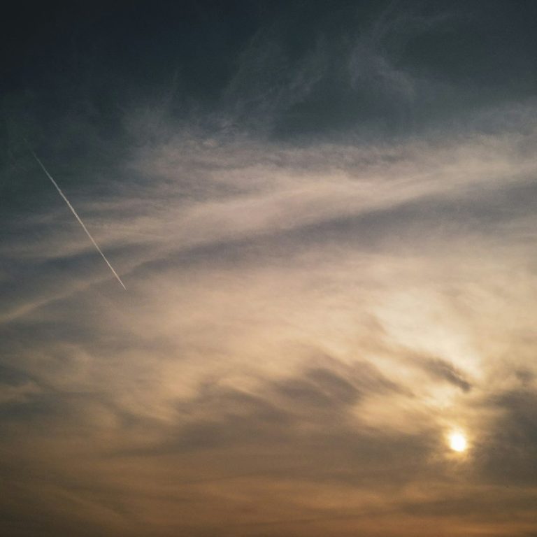 Ozonoterapia Cielo nublado al atardecer, con tonos anaranjados y una estela de avión. Ozonoterapia